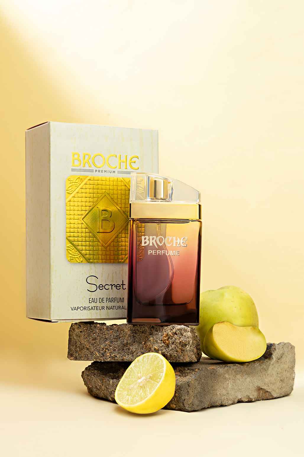 broche-secret-eau-de-parfum-50ml-bottle-and-packaging-on-rocks-with-apple-and-lemon-slices